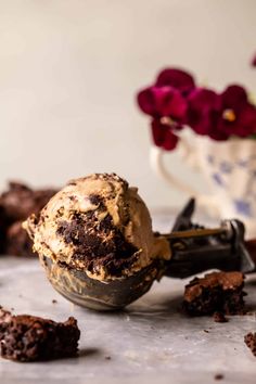 a scoop of ice cream sitting on top of a table next to chocolate cookies and flowers