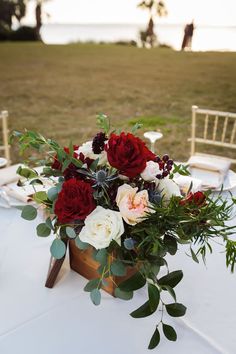 a vase filled with red and white flowers sitting on top of a table next to a chair