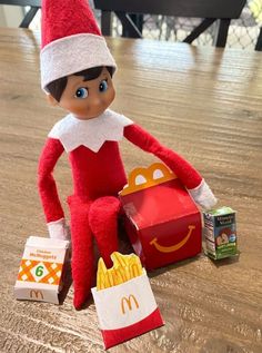 an elf is sitting on the floor next to some fries and a mcdonald's bag