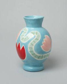 a blue vase with red and white designs on the outside, sitting against a gray background