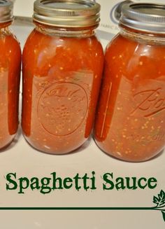 four jars filled with homemade spaghetti sauce sitting on top of a white countertop next to the words homemade spaghetti sauce