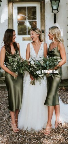 three bridesmaids laughing together in front of a house with greenery and flowers