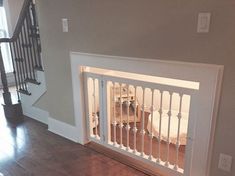 a dog gate in the middle of a room next to a stair case and wooden floor