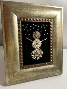 a gold frame with an image of a snowman made out of beads and pearls