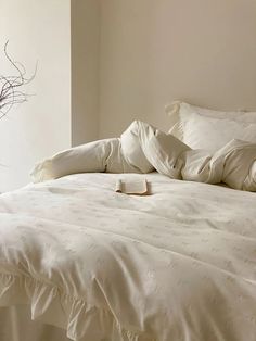 an unmade bed with white sheets and pillows