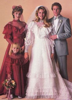 the bride and groom are posing with their two children in front of an orange wall