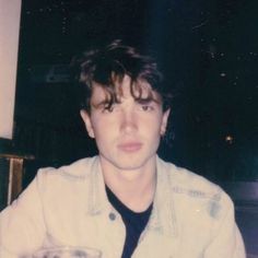 a young man sitting at a table with a drink in his hand