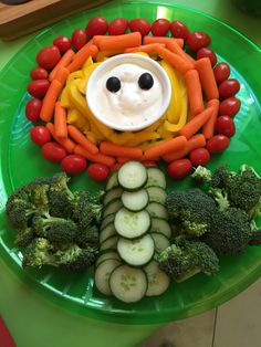 a green plate topped with lots of veggies and a face made out of vegetables