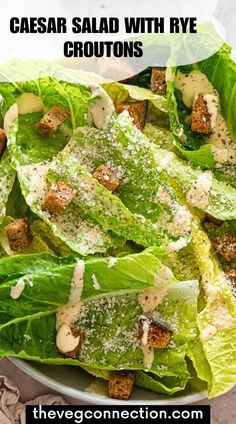 caesar salad with rye croutons in a white bowl on top of a table