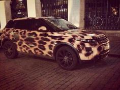 a leopard print land rover parked in front of a building