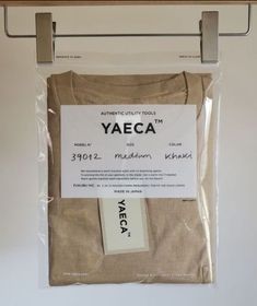 the yaeca t - shirt is packaged in a clear plastic bag on a metal hanger