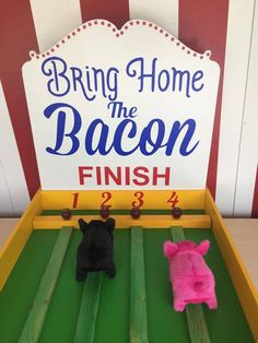 two stuffed animals sitting in front of a sign that says bring home the bacon finish