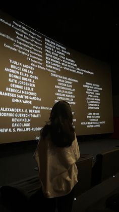 a woman standing in front of a projection screen with words projected on the wall behind her