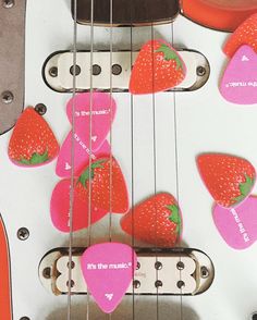 an electric guitar with pink pickers on it's neck and the strings are shaped like strawberrys