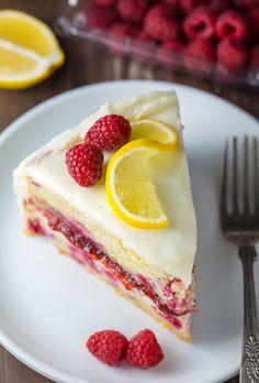 a piece of cake with raspberries and lemons on the side next to a fork