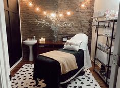 a spa room with a brick wall and lights on the ceiling, along with a black and white area rug