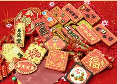 an assortment of decorated cookies on a red tablecloth with chinese writing and decorations around it