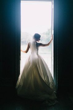 a woman in a wedding dress is standing at the open door with her arms outstretched