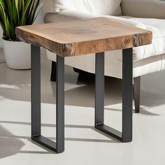 a wooden table sitting on top of a white floor next to a chair and potted plant