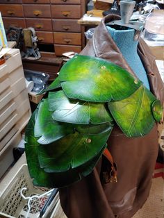 a large green leaf on top of a mannequin's head in a room