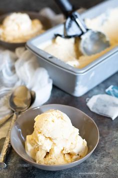 scoops of ice cream in a bowl with spoons next to it on a table