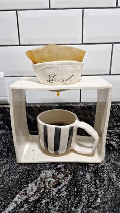 a coffee cup sitting on top of a counter next to a white and black bowl