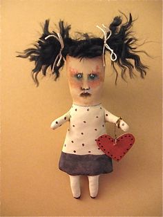 a doll is hanging on the wall with her hair blowing in the wind and holding a heart