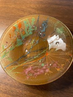 a plate that has some kind of animal in it on a wooden table with paint splatters all over it