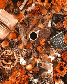 a table topped with books, candles and pumpkins next to a cup of coffee