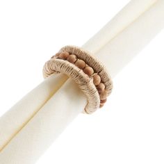 a close up of a napkin ring on top of a white cloth with wood beads