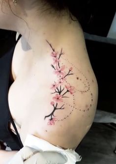 a woman's back with pink flowers and dots on her stomach, tattooing it