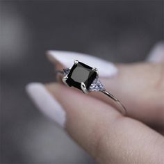 a woman's hand holding a black and white diamond ring