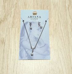 two necklaces with pearls on them sitting on a wooden table in front of a card