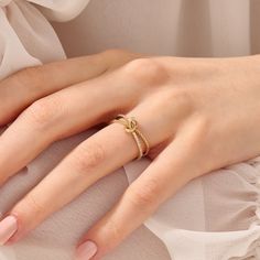 a woman's hand wearing a gold ring with two intertwined rings on it