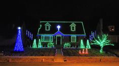 a house is lit up with christmas lights in the front yard and trees on the lawn