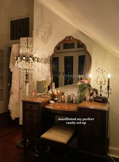 a vanity with a mirror and candles on it in a room that has a slanted ceiling