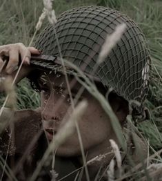 a man in a field with a helmet on his head and one hand over his face