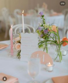 the table is set with flowers, candles and place cards for guests to sit at