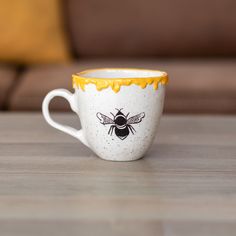 a white and yellow coffee cup sitting on top of a wooden table