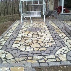 a white bench sitting in the middle of a stone walkway next to a brick patio