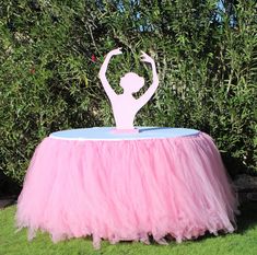 a pink tutu skirt sitting on top of a table in front of some bushes