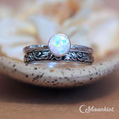 a white opal ring sitting on top of a piece of wood