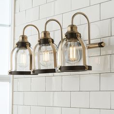 three light fixtures mounted on a white brick wall