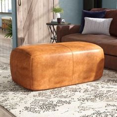 a brown leather ottoman sitting on top of a rug next to a couch and chair