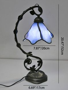 a table lamp with a blue glass shade on it's side and measurements for the base