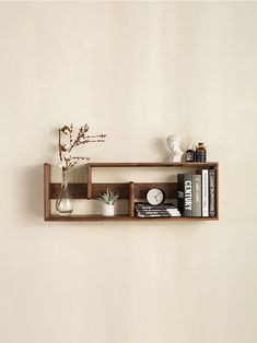 a shelf with books and vases on top of it next to a white wall