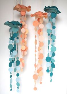 two mobiles made out of paper with circles and flowers hanging from the ceiling in front of a white wall