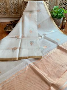 An exquisite pure 100% silk organza/kora benarasi saree in off white with copper & silver alfi buta (floral motif) woven throughout the six yards, along with a sleek golden border on either side. This saree is very stylish and classy, especially because of its simplicity and grace. The alfi (technique in Benaras weaving using two colored yarns) buta looks so stunning with the silver and copper zari as it keeps alternating with each motif. The pallu has a solid copper zari weaving. The fabric White Chanderi Dupatta For Celebration, White Organza Traditional Wear For Celebration, White Chanderi Dupatta With Self Design, White Traditional Wear With Sheer Dupatta In Tissue Silk, White Cotton Silk Dupatta For Diwali, White Traditional Wear With Zari Weaving In Tissue Silk, White Tissue Silk Dupatta With Zari Work, White Tissue Silk Traditional Wear With Zari Weaving, White Cotton Silk Dupatta For Festivals