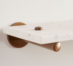 a white shelf with two brass knobs on it