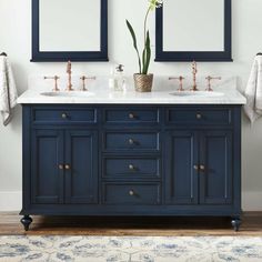 two sinks and mirrors in a bathroom with blue cabinets